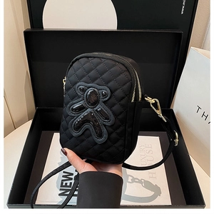 Detailed view of black quilted crossbody phone bag with sequined bear in a premium gift box