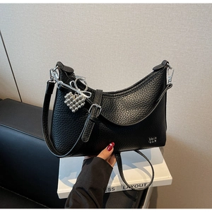 Detail of black crescent bag with lychee texture and heart-shaped beaded charm