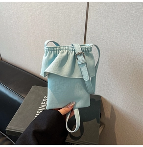 Détail du sac seau bleu clair avec bordure volantée et cuir grainé de style litchi