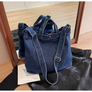 Close-up of vintage blue denim tote bag with adjustable strap on a black silk backdrop