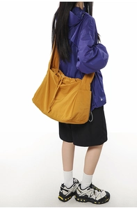 Détail du sac bandoulière jaune moutarde avec cordon de serrage et texture en nylon durable