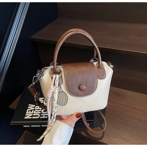 Detail of a beige and brown contrast mini dumpling bag with tennis racket charm
