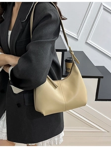Chic beige faux leather underarm crescent bag with gold buckle on a stylish model