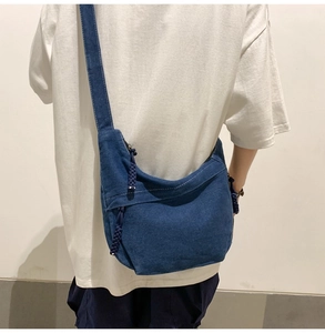 Blue denim hobo bag featuring a woven rope zipper detail worn by a model in profile