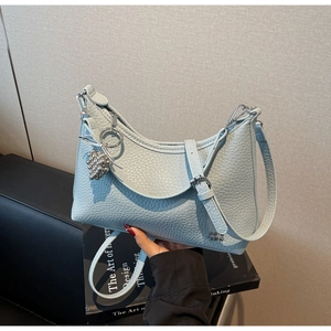 Detail of light blue lychee leather crescent bag with silver buckle and grape pendant