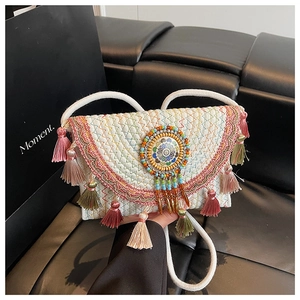 Close-up of bohemian woven shoulder bag featuring colorful tassels and ethnic ornament