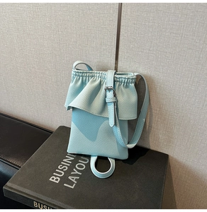 Gros plan sur le sac seau bleu clair à volants avec texture cuir grainé lychee