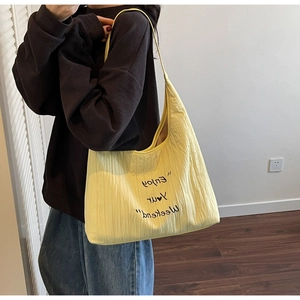 Detail of light yellow embroidered canvas tote bag with Enjoy Your Weekend slogan