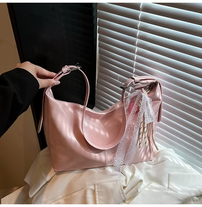 Detailed view of pink hobo bag with white lace trim and striped colorful cord pendant