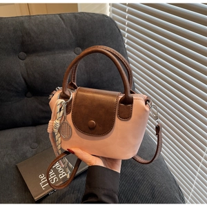 Detail of a mini crossbody bag with pink and brown color block and tennis racket charm