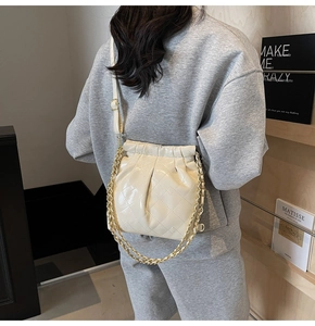 Detail of quilted beige shoulder bag with gold chain strap and drawstring closure