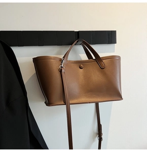 Brown faux leather bucket bag displayed on a minimalist black hanger with adjustable strap