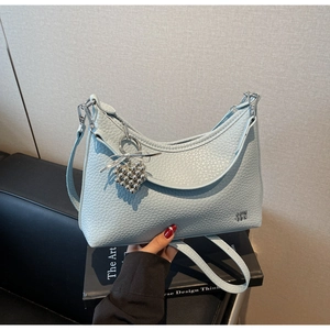 Detail of light blue lychee pattern leather shoulder bag with silver heart charm and metal logo