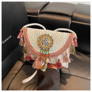 Detail view of colorful fringe tassels and beaded disc on ethnic knit crossbody bag