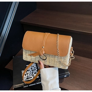 Detail of woven straw and brown leather shoulder bag with gold chain and ring buckle