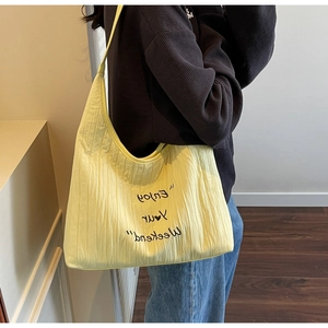 Detail of the yellow pleated canvas tote bag with 'Enjoy Your Weekend' text print