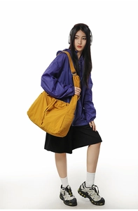 Grand sac à bandoulière jaune à cordon porté par un modèle avec poches latérales