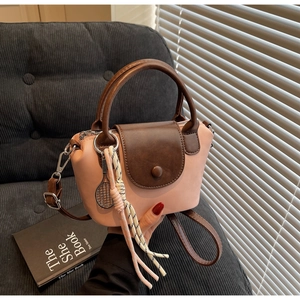 Close-up of pink and brown leather handbag with tennis racket charm and tassel detail