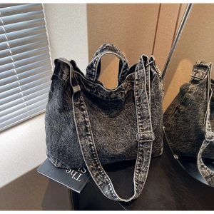 Detail of a vintage washed denim tote bag showing the dual handles and adjustable shoulder strap