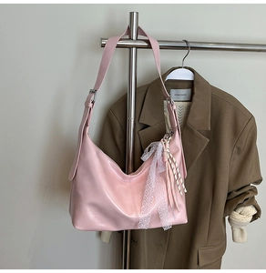 Detail of pink glossy hobo bag featuring lace bow charms and textured woven rope decor