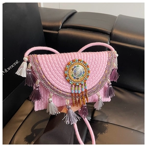 Detail of pink straw bag with colorful beadwork and purple tassels in ethnic design