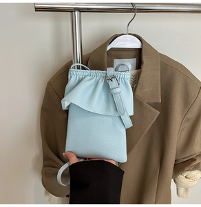 Détail du mini sac seau bleu clair avec texture cuir grainé et fermeture à volants