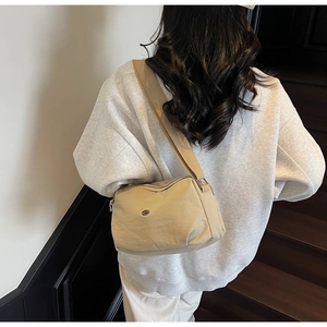 Détail d'un sac bandoulière beige multicouche avec large sangle en tissu sur modèle