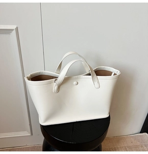 Detail shot of a white minimalist bucket bag with inner lining on a dark wood stool