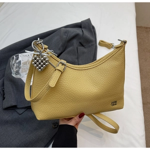 Close-up of yellow lychee grain leather tote bag with silver hardware and heart charm