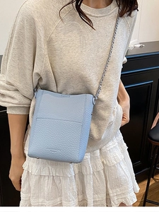 Light blue pebbled leather bucket bag with chain strap and metal bottom studs