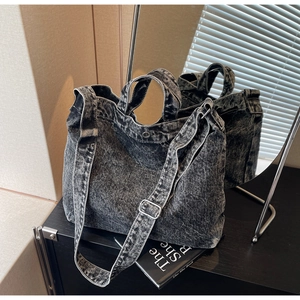 Detail of washed denim tote bag showing sturdy handles and adjustable shoulder strap