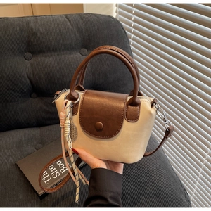 Detail of the cream and brown faux leather handbag with a colorful woven charm strap