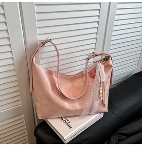 Detail of pink hobo bag with lace bow and heart charm on a minimalist white backdrop