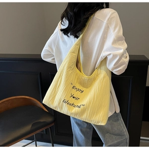 Detail of a lemon yellow pleated canvas tote bag with Enjoy Your Weekend embroidery