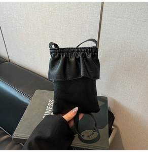 Détail du petit sac seau noir en cuir grainé avec bordure volantée et bandoulière