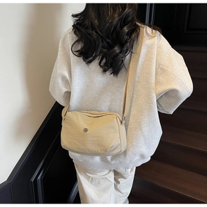 Détail du sac bandoulière beige en nylon avec sangle large réglable et logo métal