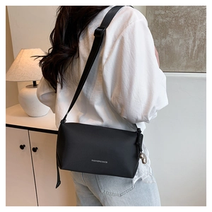 Détail du sac à bandoulière noir minimaliste avec sangle réglable et petit pendentif