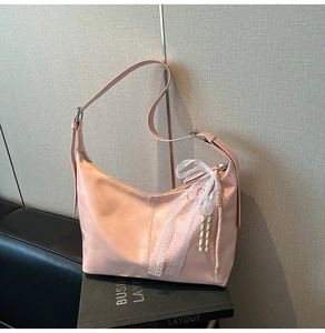 Detail of pink PU leather dumpling bag featuring lace bows and woven charms