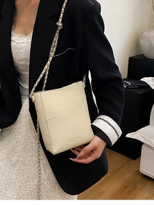 Minimalist beige pebble leather bucket bag with gold chain strap for women