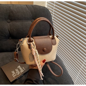 Close-up of stylish mini beige handbag with dark brown trim and tennis racket charm