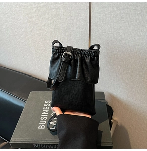 Détail du mini sac bandoulière noir avec cordon de serrage froncé et boucle argentée