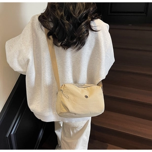 Vue latérale d'un sac bandoulière croissant beige porté par un mannequin