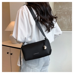 Détail du sac bandoulière noir avec imprimé Fashion et pendentif en forme de cœur argenté