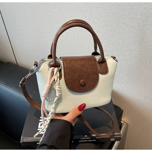 Detail of color-block dumpling bag with tennis racket charm and metal zipper