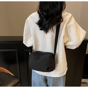 Model view showing the black nylon crossbody bag with minimalist logo and adjustable strap