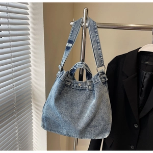 Detail of vintage denim tote bag with washed blue texture and silver metallic buckles