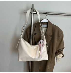 Close-up of beige Hobo bag with glossy leather texture and stylish lace stripe charm