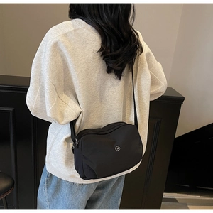 Modèle portant le sac bandoulière en nylon noir montrant la taille et la sangle ajustable