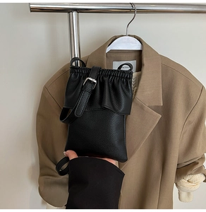 Gros plan d'un sac seau noir en cuir grainé avec design plissé et bandoulière fine