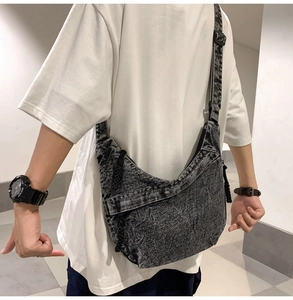 Close-up of grey washed denim crescent tote bag with adjustable wide strap on model